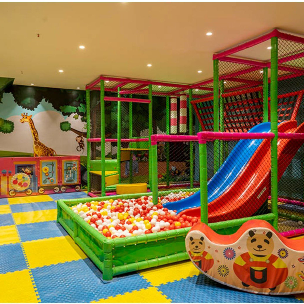 A vibrant K square edutainment indoor play area for children featuring a slide and a jungle gym, providing endless fun and adventure