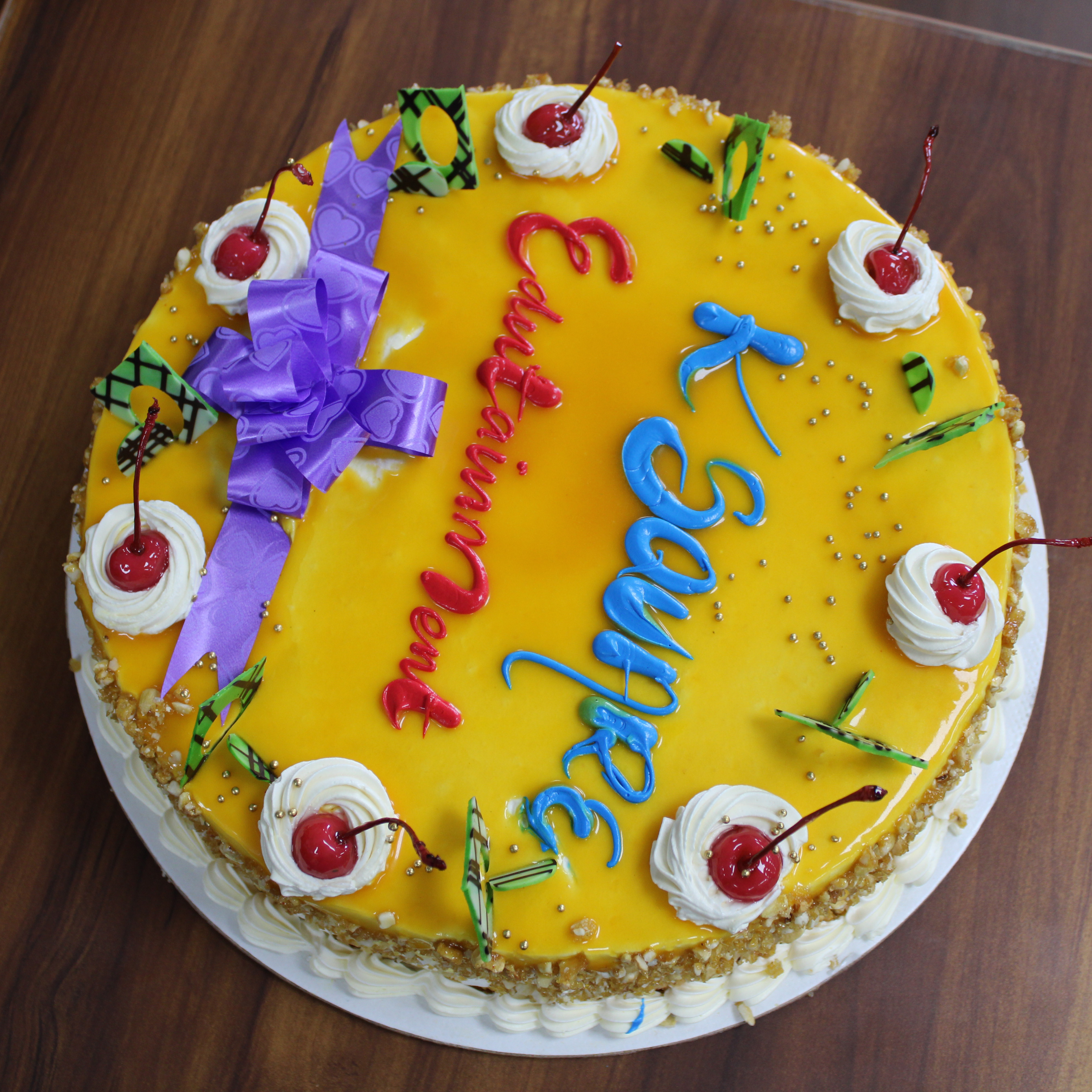 A delicious cake topped with cherries and a decorative ribbon.