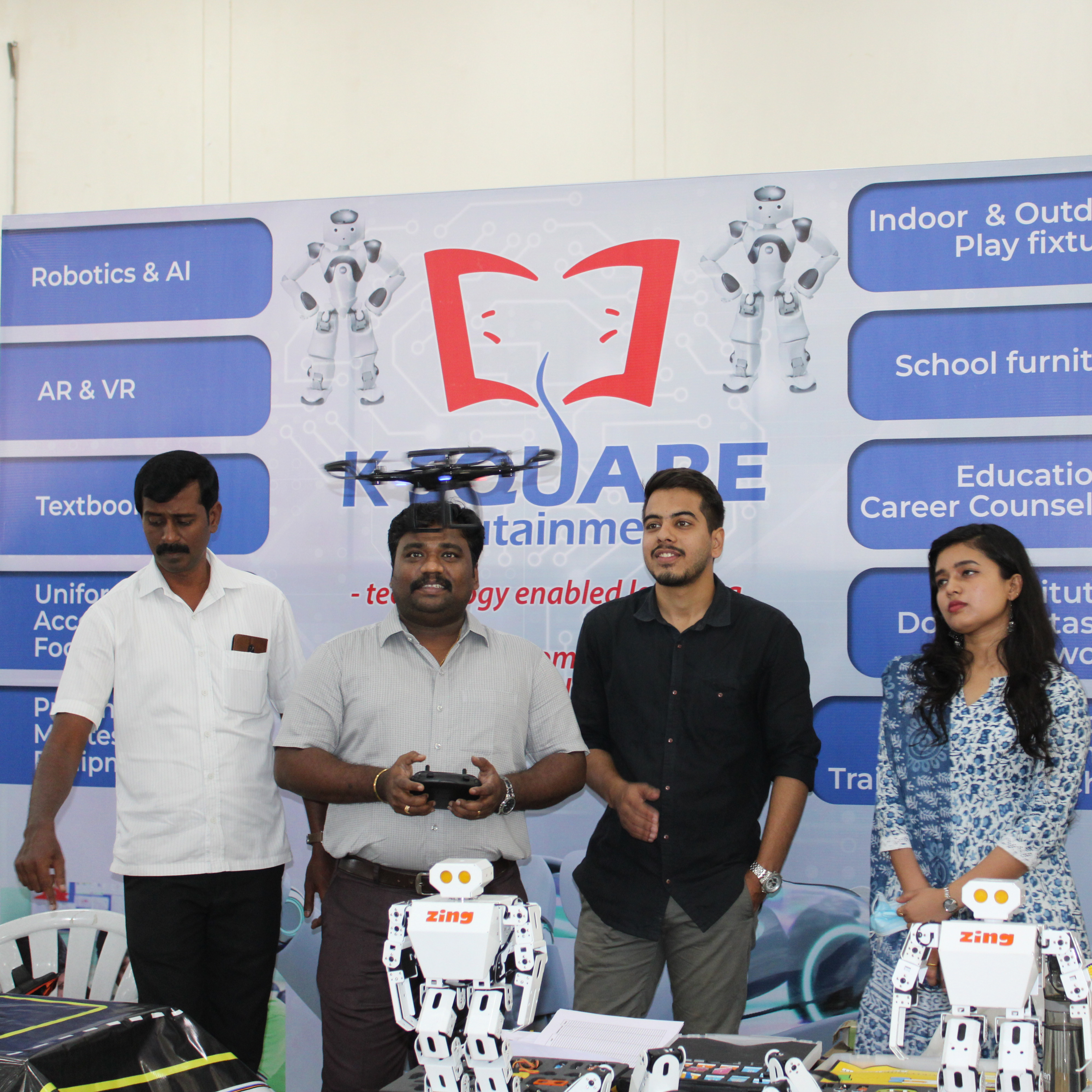 A diverse group gathered around a table, engaged in conversation, with a K square edutainment robot present.