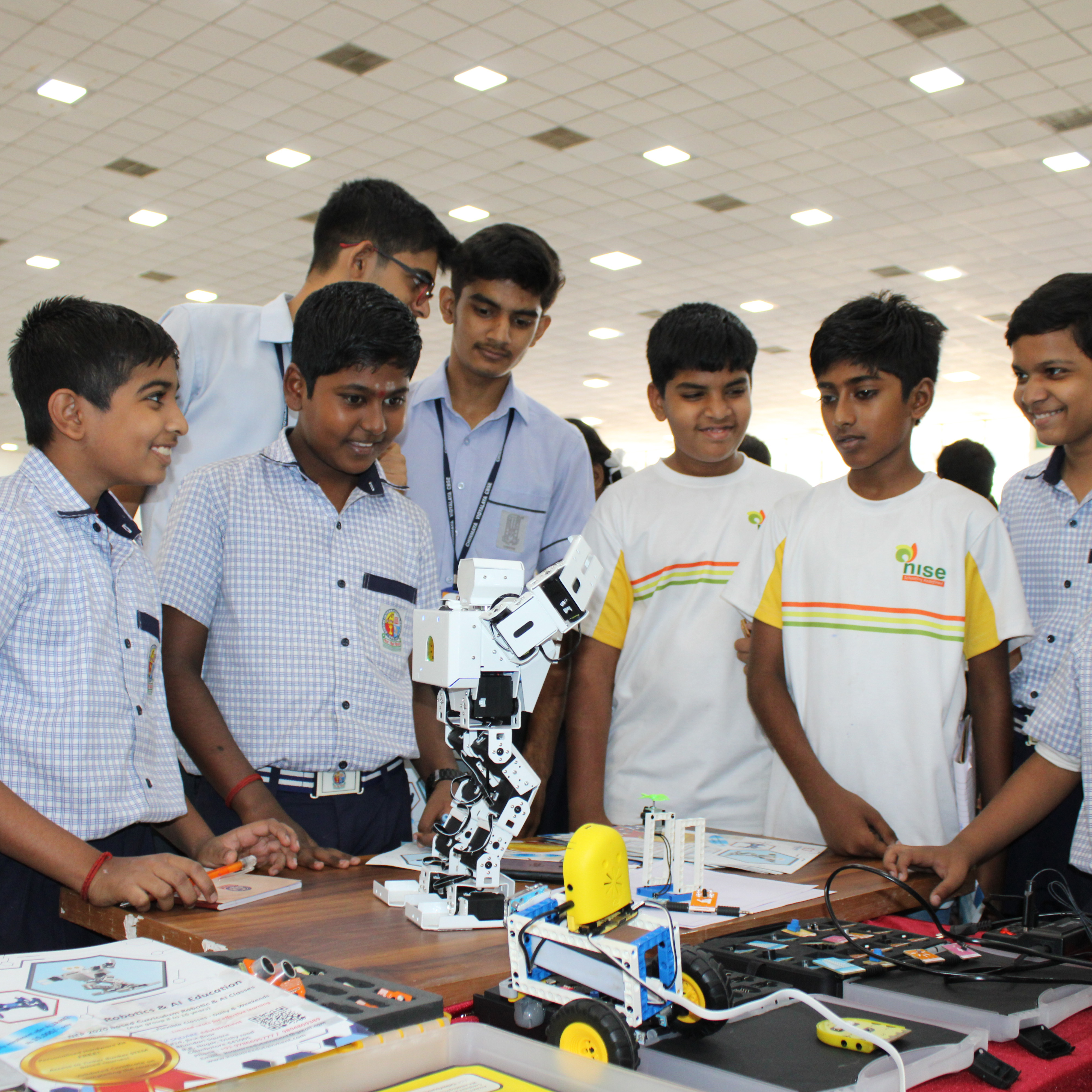 A group of young boys fascinatedly observing a K square edutainment robot in front of them.