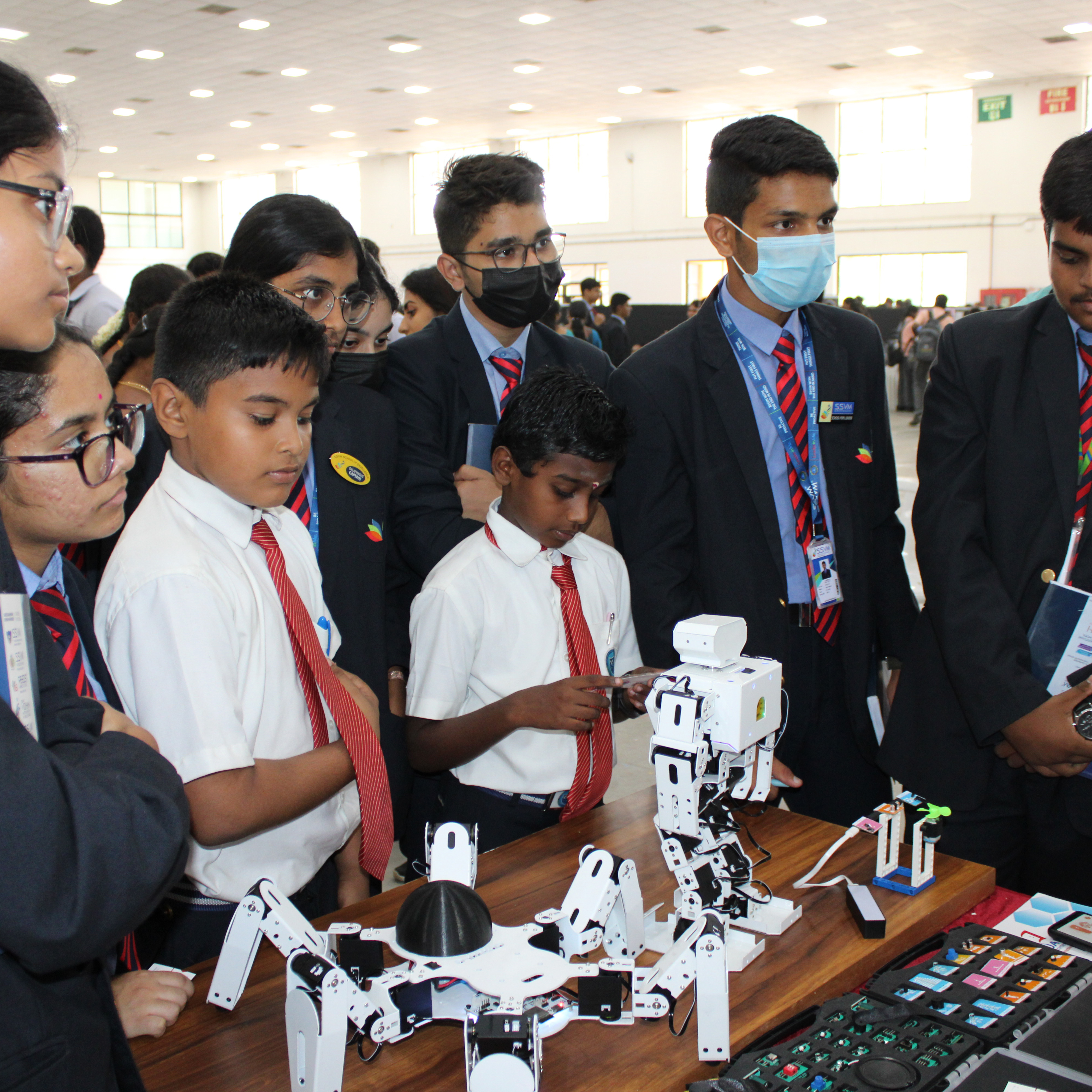 Group of kids in uniforms watching a K square edutainment  robot during the Exhibition