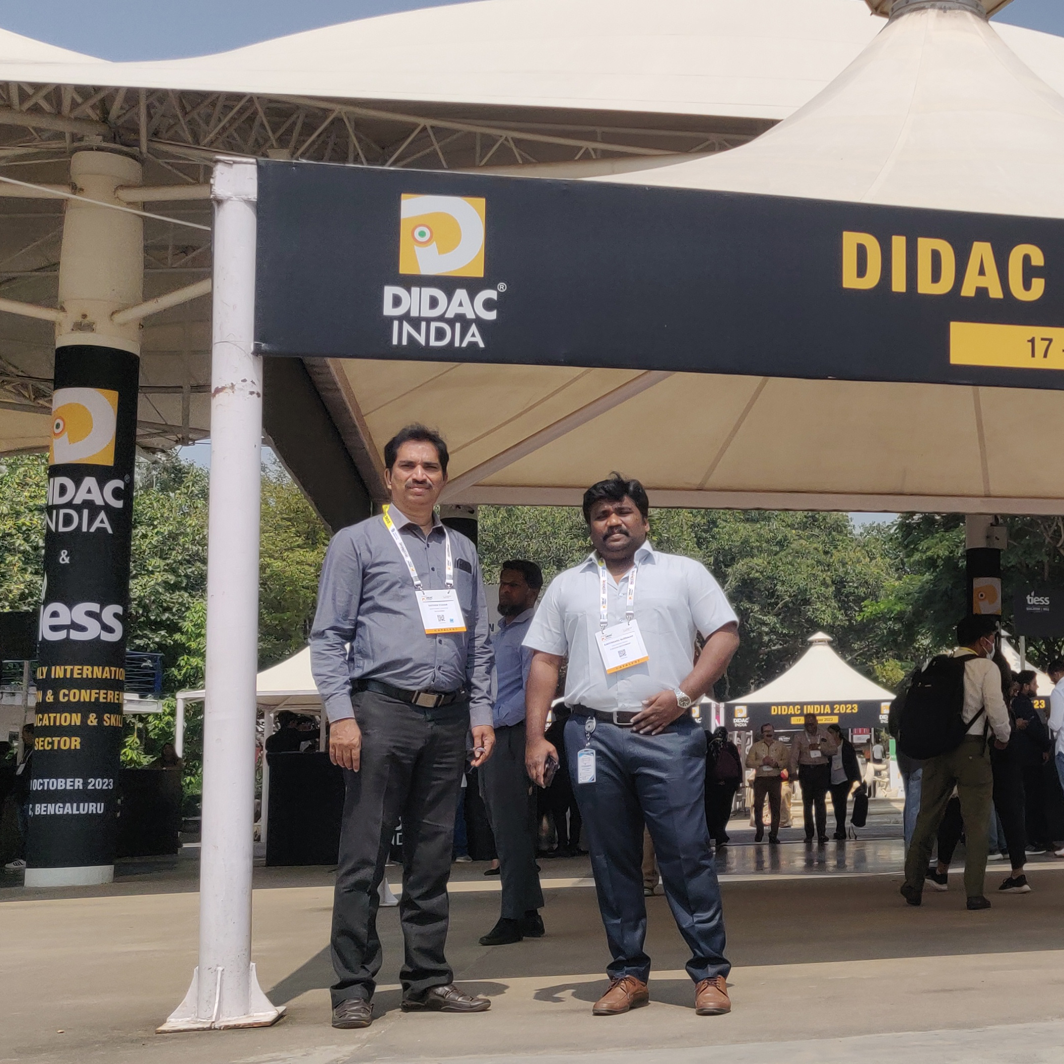 Two men from K Square Edutainment standing under a tent in the Didac India event