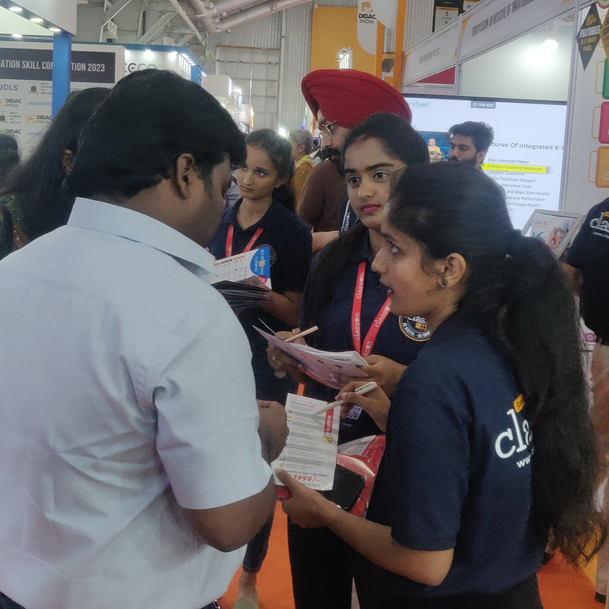  People of various backgrounds gathered around a table at an event, interacting and socializing.